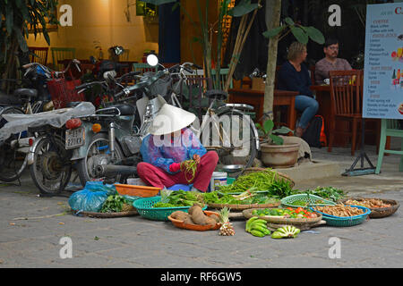 Hoi An, Vietnam - 20 dicembre 2017. Un venditore ambulante tipi ortaggi in attesa per i clienti su una strada del centro storico UNESCO di cui Vietnames Foto Stock