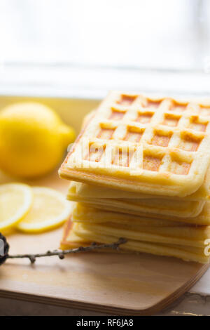 Wafer Viennese pila e fette di limone. Fette di limone su una tavola di legno. I frutti vengono tritati. Sour limone. Gli agrumi Foto Stock