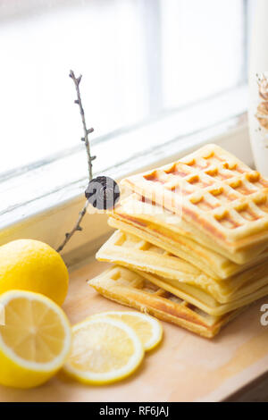 Wafer Viennese pila e fette di limone. Fette di limone su una tavola di legno. I frutti vengono tritati. Sour limone. Gli agrumi Foto Stock