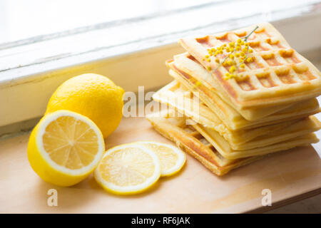 Wafer Viennese pila e fette di limone. Fette di limone su una tavola di legno. I frutti vengono tritati. Sour limone. Gli agrumi Foto Stock