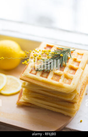 Wafer Viennese pila e fette di limone. Fette di limone su una tavola di legno. I frutti vengono tritati. Sour limone. Gli agrumi Foto Stock