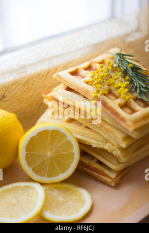 Wafer Viennese pila e fette di limone. Fette di limone su una tavola di legno. I frutti vengono tritati. Sour limone. Gli agrumi Foto Stock