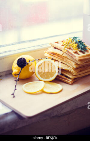 Wafer Viennese pila e fette di limone. Fette di limone su una tavola di legno. I frutti vengono tritati. Sour limone. Gli agrumi Foto Stock