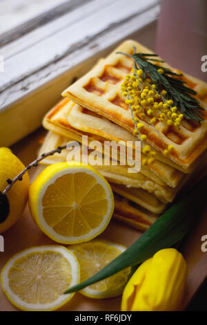 Wafer Viennese pila e fette di limone. Fette di limone su una tavola di legno. I frutti vengono tritati. Sour limone. Gli agrumi Foto Stock