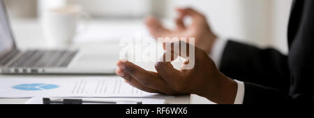 Foto orizzontale imprenditore africano seduto alla scrivania facendo esercizi yoga Foto Stock