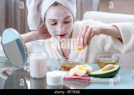 Bella felice giovane donna con cosmetici naturali maschera sul viso. Il concetto di cura della pelle e trattamenti Spa a casa Foto Stock
