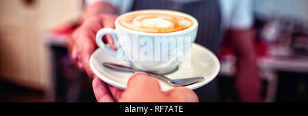 Immagine ritagliata del cliente a prendere il caffè da cameriere presso il cafe Foto Stock