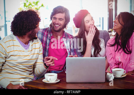 Ridere gli amici sorseggiando un caffè con laptop Foto Stock