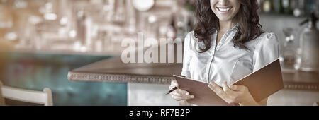 Sorridente cameriera tenendo un file nel ristorante Foto Stock