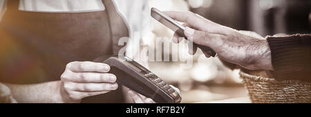 Il cliente il pagamento fattura tramite lo smartphone utilizzando la tecnologia NFC in cafe Foto Stock