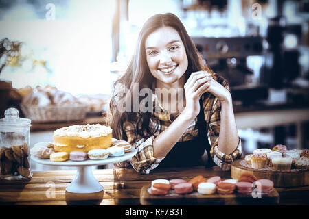 Ritratto di cameriera permanente al contatore con dessert Foto Stock