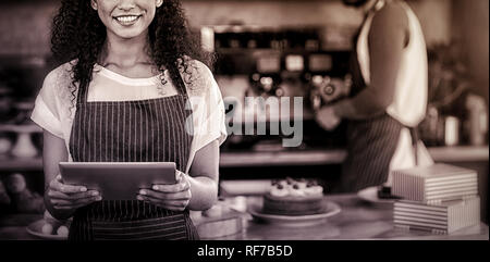 Sorridente cameriera utilizzando digitale compressa al contatore in cafÃƒÂ© Foto Stock