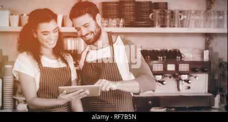 Sorridente cameriere e cameriera con tavoletta digitale al bancone Foto Stock