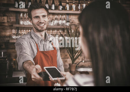 Donna di effettuare il pagamento tramite la tecnologia NFC sul telefono cellulare Foto Stock