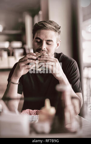 L'uomo mangiare hamburger Foto Stock