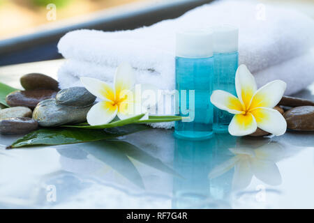 Due fiori e un po' di bottiglie con olio per massaggi Foto Stock