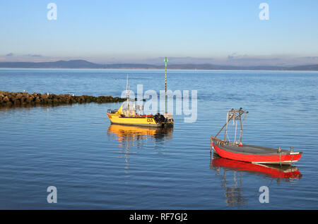 Due piccole barche ancorate ad alta marea off lungomare a Morecambe con la famosa vista di tutta la baia di Morecambe verso il distretto del lago. Foto Stock