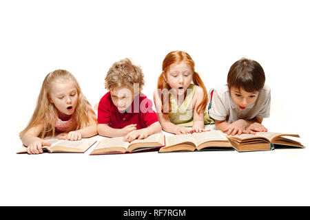 La sorpresa ragazzo ragazzi e ragazze che stabilisce con libri a studio, sorridente, ridendo, isolato su bianco. Giorno del libro, l educazione, la scuola, capretto, la conoscenza, l'infanzia, l'amicizia, lo studio i bambini concept Foto Stock