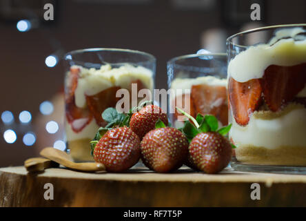 Magnolia dessert servito sul piatto di legno. Il dessert in bicchieri di vetro decorate con strawberriesand cucchiai di legno. Foto Stock