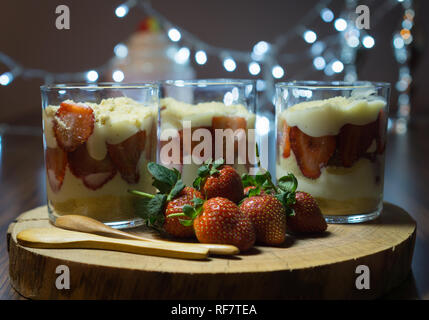 Magnolia dessert in bicchieri di vetro. Decorate con cucchiai di legno e le fragole e il bokeh di fondo gli effetti di luce in background. Foto Stock