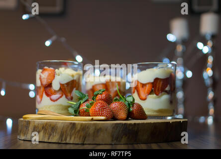 Tre tazze di Magnolia dessert. Magnolia dessert servito in bicchieri sul piatto di legno con le fragole. Foto Stock