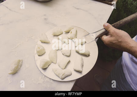 Piccole palline di pasta sulla paletta. In casa pane di piccole dimensioni. Foto Stock