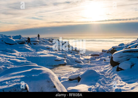 Due escursionisti in cima Kinder rovina su Kinder Scout nel Parco Nazionale di Peak District, UK. Pomeriggio d'inverno. Foto Stock