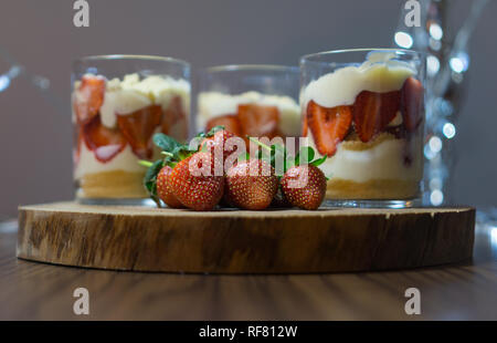 Magnolia dessert. Chiudi vista frontale.Magnolia dessert servito sul piatto di legno con fragole e cucchiai di legno. Foto Stock