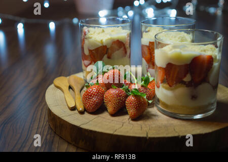 Magnolia dessert in CUPS. Servite sul piatto di legno con strawberriesand cucchiai di legno. Chiudi vista frontale. Foto Stock