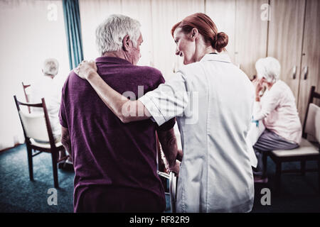 Un infermiere che assiste un senior usando un walker Foto Stock