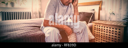 Frustrati senior uomo seduto sul letto Foto Stock