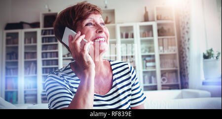 Senior Donna che parla al telefono cellulare in salotto Foto Stock