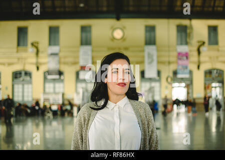Bella singola adulta e matura donna allegra rilassante sulla stazione ferroviaria durante l'attesa per l arrivo del suo treno. Foto Stock