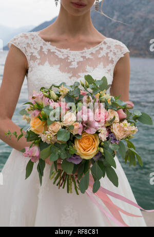 La sposa detiene un rosa pesca bouquet nuziali, close up Foto Stock