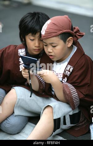 Giappone Tokyo: Santuario festival, chiamato Matsuri. Bambini che giocano con un computer portatile di gioco. Foto Stock