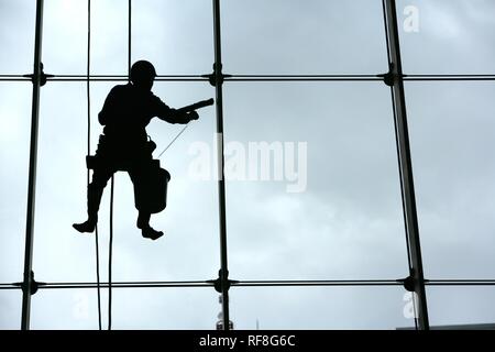 Il lavavetro appeso contro la facciata di vetro di un grattacielo, Tokyo, Giappone, Asia Foto Stock