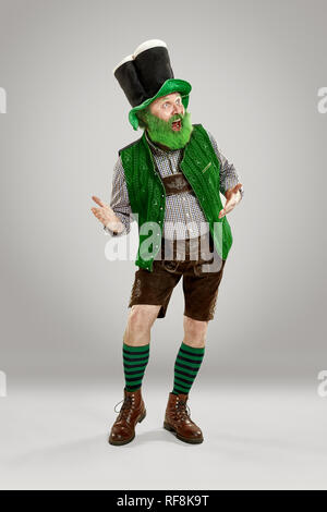 Un sorriso felice uomo senior in un leprechaun hat con barba di studio. Egli celebra la festa di San Patrizio. La celebrazione festosa, birra, vacanze, alcol, concetto di partito Foto Stock