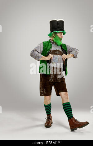 Un sorriso felice uomo senior in un leprechaun hat con barba di studio. Egli celebra la festa di San Patrizio. La celebrazione festosa, birra, vacanze, alcol, concetto di partito Foto Stock