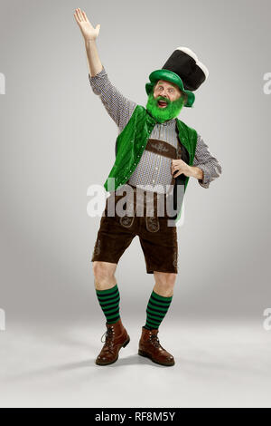 Un sorriso felice uomo senior in un leprechaun hat con barba di studio. Egli celebra la festa di San Patrizio. La celebrazione festosa, birra, vacanze, alcol, concetto di partito Foto Stock