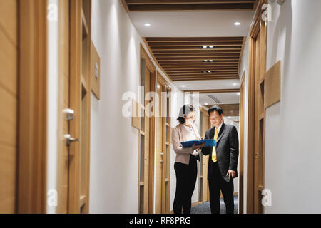 Imprenditrice spiegando di documenti a Felice Client cinesi in Bank office Foto Stock