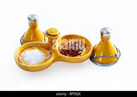 Arancione tradizionale marocchino smaltata ceramica sale e pepe piatto con sale marino e peperoncino in scaglie su sfondo bianco Foto Stock