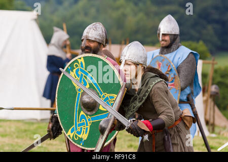Medieval re-enactors vestito di corazza e costumi del XII secolo dotato di spade e scudi ri-emanazione di combattimento del periodo Foto Stock