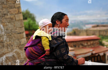 Donna tibetana che porta il bambino sulla schiena. Foto Stock