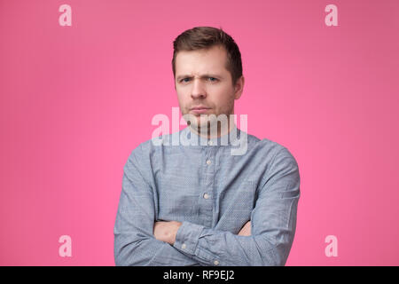 Uomo europeo tenendo le mani incrociate sul petto, guardando da sotto la fronte in piedi arrabbiato e alimentato fino Foto Stock
