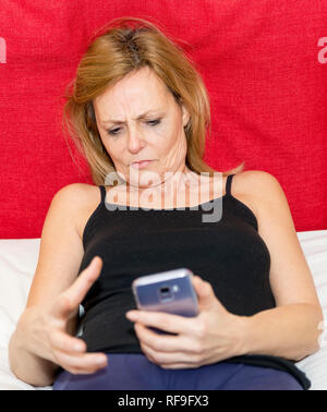 Momento di disperazione di una donna che sta guardando il display del suo smartphone Foto Stock