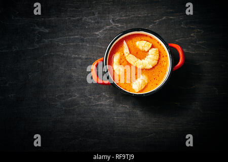 Tradizionale zuppa tailandese con gamberi e latte di cocco in una pentola di rosso Foto Stock