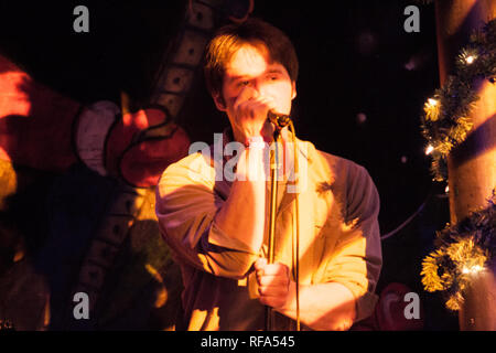 Il cantante in una band canto sul palco con colorate psichedeliche come la luce che incide su di essi in un spettacolo musicale durante le vacanze. Foto Stock