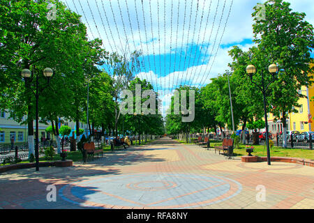 Strada di Bielorusso città di Gomel con banchi di alberi e da appendere ghirlande. Persone in appoggio nel parco con panchine e ghirlande. Le persone a rilassarsi in città. Essere Foto Stock
