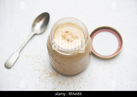 Vasetto di tahin un cucchiaio con semi seasame su sfondo bianco Foto Stock