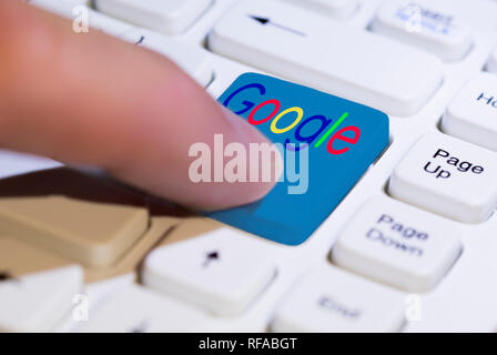 Dito che preme un pulsante di Google su un PC della tastiera del computer. Foto Stock